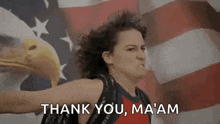 a woman is holding a bald eagle in front of an american flag and saying `` thank you , ma am '' .