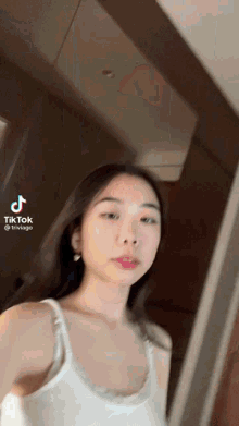 a woman in a white tank top has a tiktok icon on her face