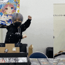 a woman wearing a mask stands in front of a poster that says mutations