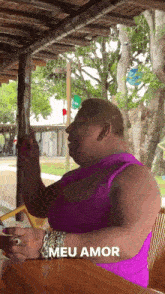 a woman in a purple tank top is sitting at a table with the words meu amor above her