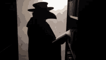 a man in a black hat is reading a book in a dark room