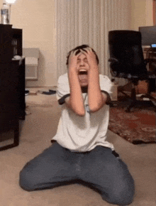 a man kneeling down with his hands on his head