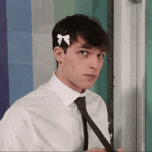 a man with a white bow in his hair is adjusting his tie