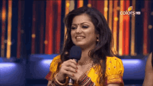 a woman is smiling while holding a microphone and the words colors hd are on the bottom