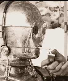 a person is lighting a cigarette in front of a robot with a helmet on