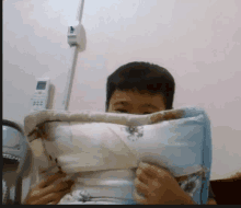 a boy covering his face with a pillow and a remote control in the background