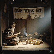 a man sits under a dukun prediksi togel banner