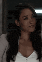 a close up of a woman 's face wearing a white shirt and a grey jacket .