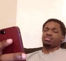 a man is sitting on a couch holding a cell phone .