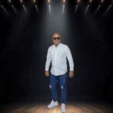 a man wearing sunglasses and a white shirt is dancing on stage
