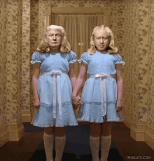 two people dressed as twins holding hands in a hallway with muglife.com on the bottom