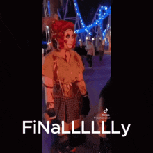 a woman in a scary costume is standing in front of a roller coaster and says finally .