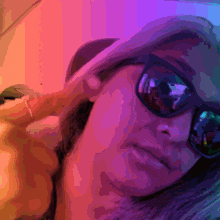a woman wearing sunglasses and a hat takes a picture of herself