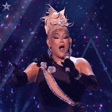 a woman singing into a microphone on a stage with a star behind her