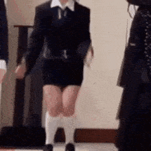 a woman in a black suit and white socks is dancing in a room .