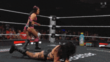 two women wrestling in a ring with a bottle of prime on the side