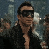 a man wearing a black mask and a leather jacket with a netflix logo on the bottom right