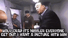 a man in a suit is talking to a group of men with the caption holy crap it 's nibbler everyone