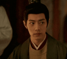 a man wearing a green robe and a hat with the letter g on it
