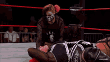 a woman with red hair is standing in a wrestling ring with a red background .