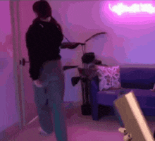 a person is standing in a room with a couch and a neon sign .