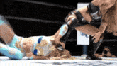 two women are wrestling in a ring and one is wearing a blue and white outfit