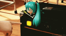 a cartoon character with blue hair and headphones is sitting on a black box