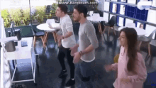 a group of people are dancing in a room with tables and chairs