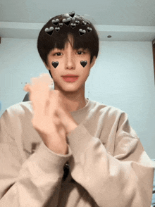 a young boy with hearts on his face makes a heart with his hands