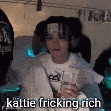a woman with a bandana on her head is holding a bunch of money and says kattle fricking rich