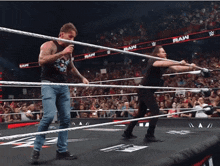 two men in a wrestling ring with the word raw written on the ropes