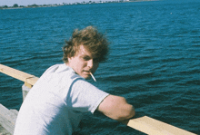 a man is smoking a cigarette while looking out over the water