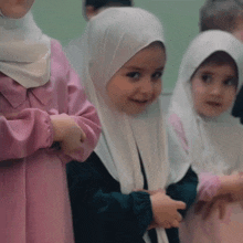 a girl wearing a pink dress and a white hijab