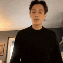 a man in a black sweater is standing in a living room