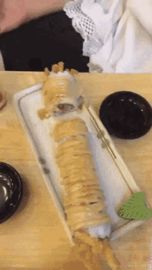 a very long sushi roll is sitting on a white plate on a table