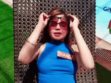 a woman wearing sunglasses and a blue top with bianca on it