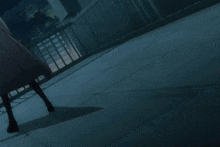 a person in a green shirt is walking down a dark sidewalk