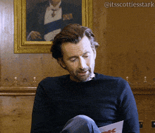 a man sitting in front of a painting with the hashtag @itsscottiesstark on the bottom