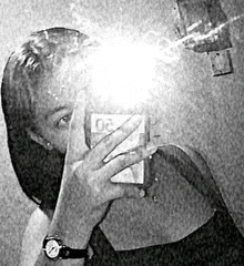 a black and white photo of a woman taking a selfie in a mirror .