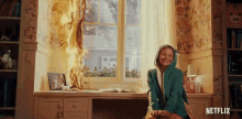 a girl is sitting in front of a window with a fire coming out of the window .