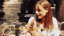 a woman sits at a table holding a dog