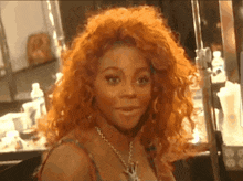 a woman with red hair and a necklace is looking at the camera