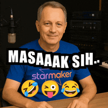 a man wearing a blue shirt that says starmaker sits in front of a microphone