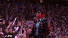 a man in a leather jacket stands in front of a crowd with the word vlipsy on the bottom