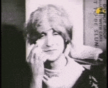 a black and white photo of a woman 's face with a sign in the background that says ' dont drop '
