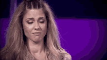 a close up of a woman 's face with her eyes closed and her hair in a bun .