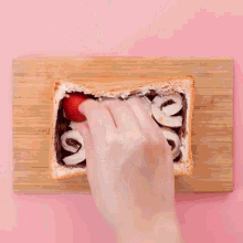 a slice of bread with strawberries and marshmallows on it on a wooden cutting board
