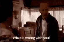 a man is standing in a room talking to another man .