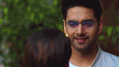 a man wearing glasses is smiling in front of a blurry background