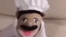 a close up of a puppet wearing a chef 's hat and a chef 's mask .